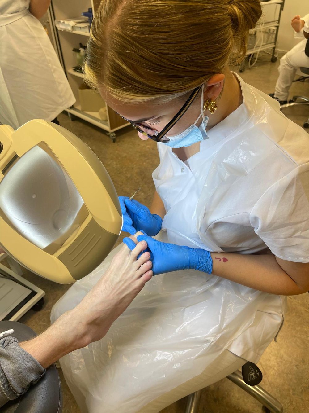 Aan het werk met mondkapje, spatscherm en handschoenen tijdens een pedicure behandeling